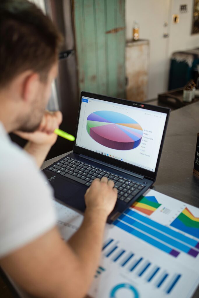 Focused man analyzing colorful bar and pie charts on laptop in modern office.